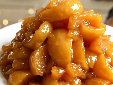 A top-down view of peeled apple wedges, butter, and rosemary in a slow cooker.
