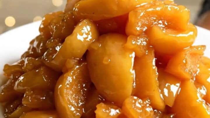 A top-down view of peeled apple wedges, butter, and rosemary in a slow cooker.
