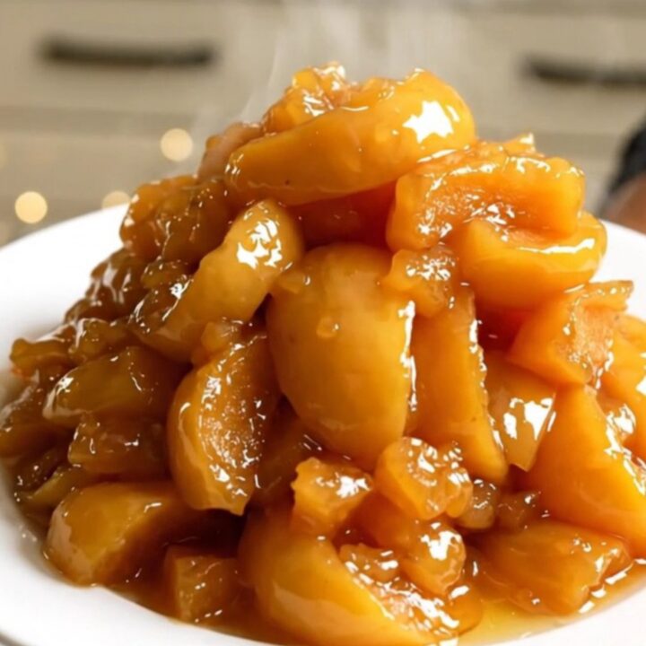 A top-down view of peeled apple wedges, butter, and rosemary in a slow cooker.