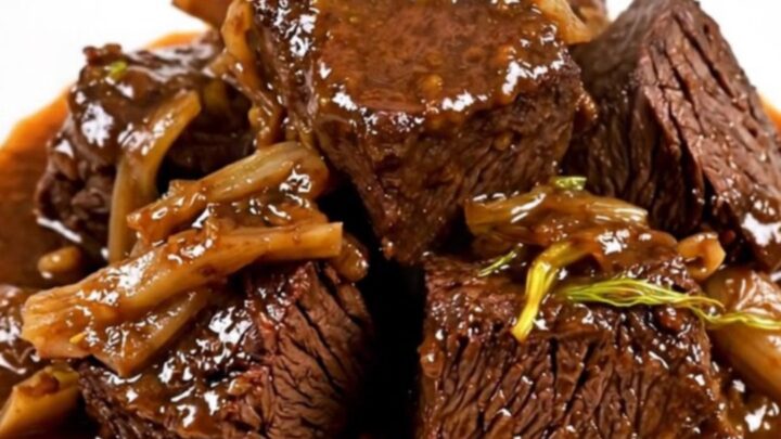 A close-up of glossy, braised beef cheeks and soft fennel slices served on a white plate.