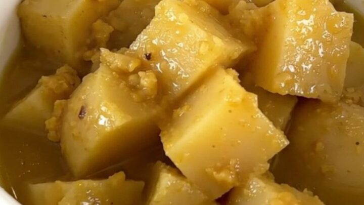 A rustic white bowl filled with steaming rutabaga and potato stew, showcasing tender vegetable chunks in a clear