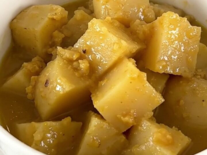 A rustic white bowl filled with steaming rutabaga and potato stew, showcasing tender vegetable chunks in a clear