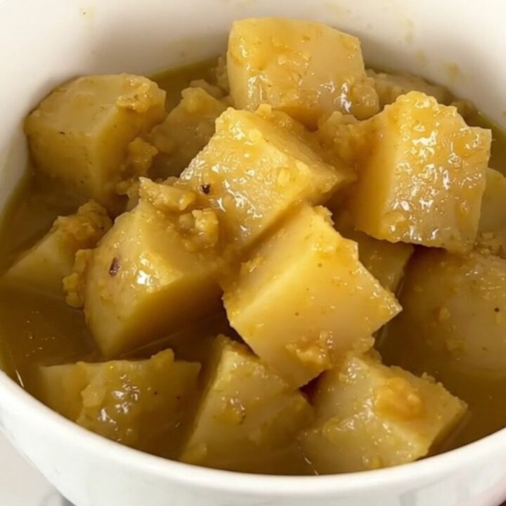 A rustic white bowl filled with steaming rutabaga and potato stew, showcasing tender vegetable chunks in a clear