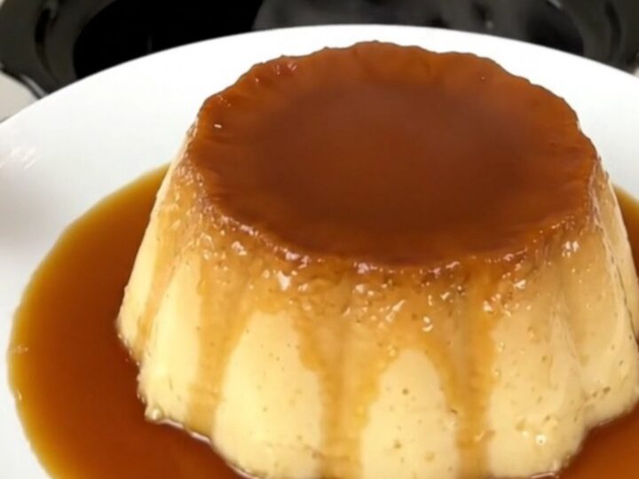 A top-down view of a black slow cooker insert showing the layered ingredients for a coffee caramel flan.