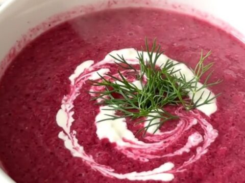 A steaming white bowl of vibrant magenta beet and potato velouté with a swirl of cream and fresh dill.