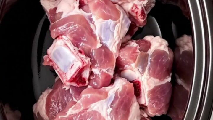 A close-up of tender pork chunks with glazed dried figs and caramelized red onions on a white ceramic plate.