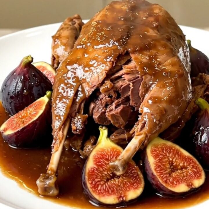 A rustic slow cooker filled with guinea fowl, fresh fig halves, and sliced shallots in a rich port wine sauce.