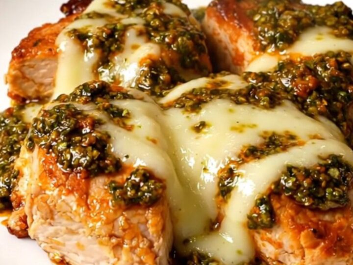 A top-down view of a slow cooker filled with chicken breasts, red pesto, and melted mozzarella cheese.