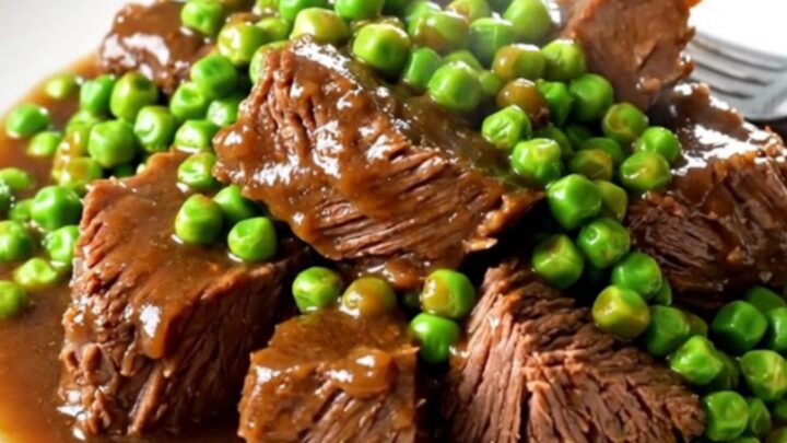 Bœuf braisé fondant servi dans une assiette blanche avec des carottes et des petits pois.