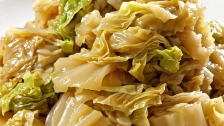 A top-down view of a slow cooker filled with layers of sliced onions and shredded white cabbage.