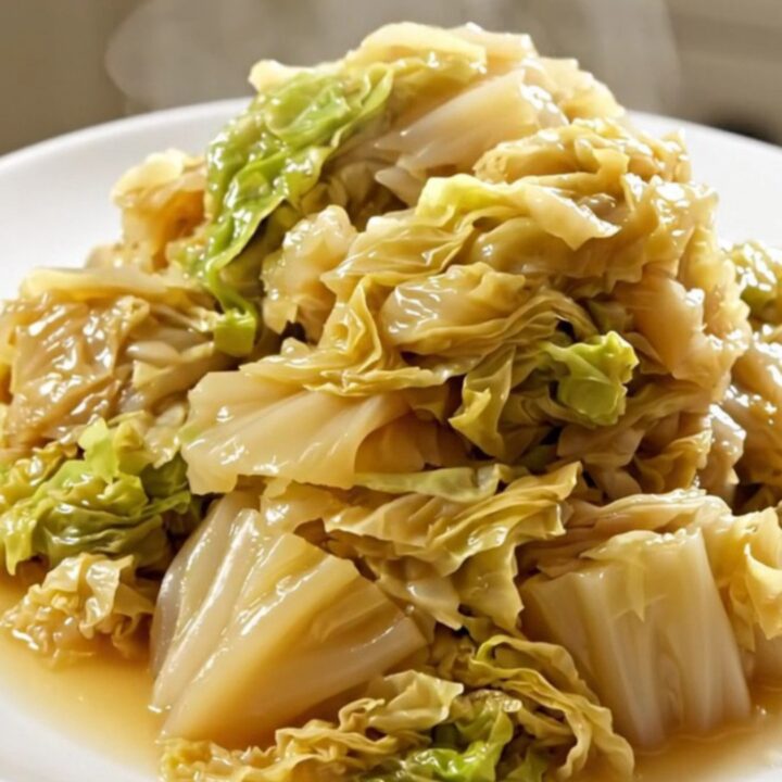 A top-down view of a slow cooker filled with layers of sliced onions and shredded white cabbage.