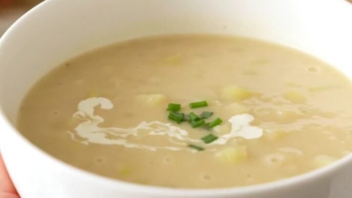 A bowl of creamy, velvety celery and potato soup steaming on a table.