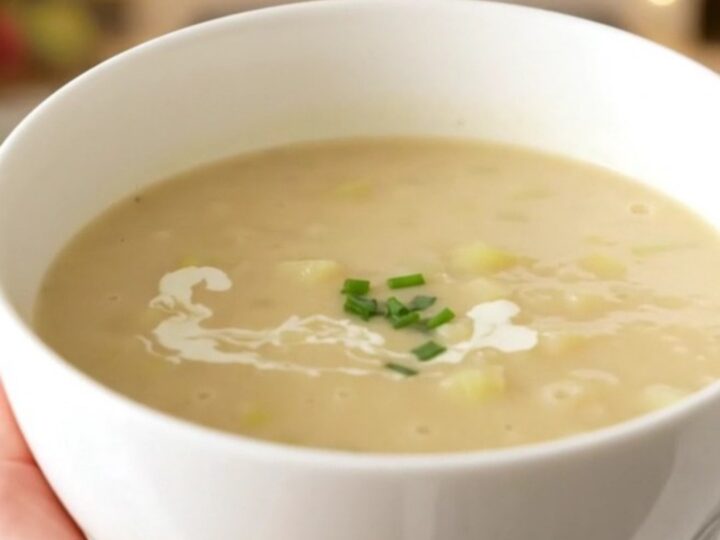 A bowl of creamy, velvety celery and potato soup steaming on a table.