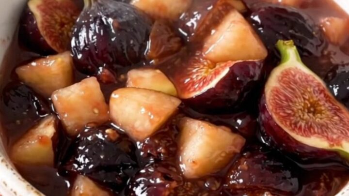 Une compote de pommes et figues brillante servie dans un bol blanc sur un fond de cuisine lumineux.