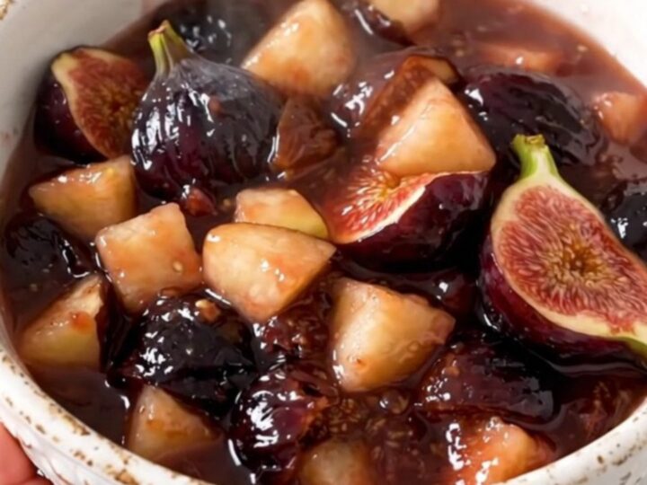 Une compote de pommes et figues brillante servie dans un bol blanc sur un fond de cuisine lumineux.