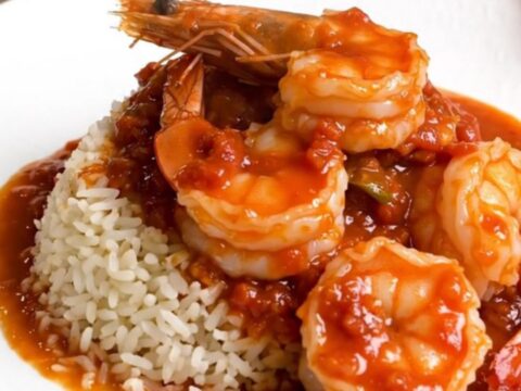 A steaming bowl of shrimp rougail served over white rice with a rich tomato sauce.