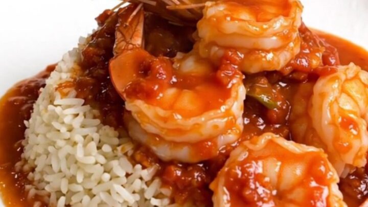 A steaming bowl of shrimp rougail served over white rice with a rich tomato sauce.