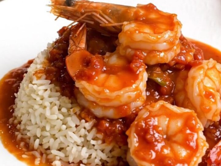 A steaming bowl of shrimp rougail served over white rice with a rich tomato sauce.