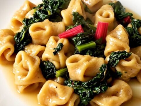 A steaming, rustic stew of figatelli sausage, diced potatoes, and Swiss chard in a white bowl.