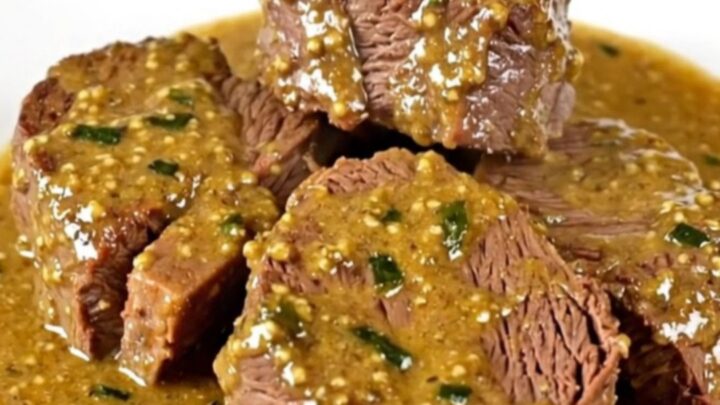 Slow cooked beef chuck slices served on a white plate with creamy tarragon mustard sauce.