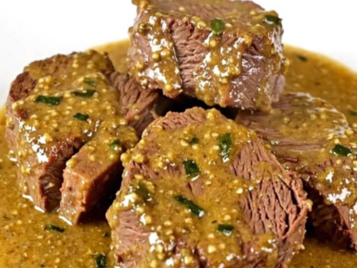 Slow cooked beef chuck slices served on a white plate with creamy tarragon mustard sauce.