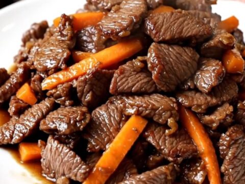 Bœuf bulgogi tendre et brillant servi sur une assiette blanche avec des carottes et oignons.