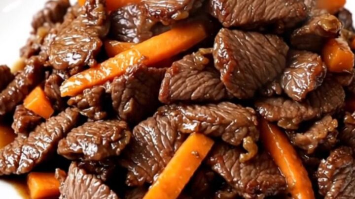 Bœuf bulgogi tendre et brillant servi sur une assiette blanche avec des carottes et oignons.