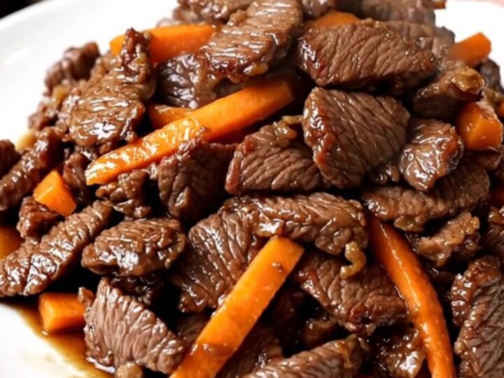 Bœuf bulgogi tendre et brillant servi sur une assiette blanche avec des carottes et oignons.
