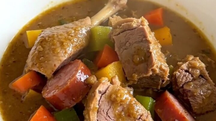 A rustic bowl of slow-cooked duck and sausage stew with carrots and turnips, garnished with fresh thyme.