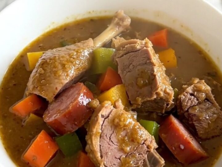 A rustic bowl of slow-cooked duck and sausage stew with carrots and turnips, garnished with fresh thyme.