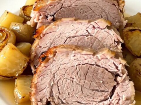 A tender, slow-cooked pork roast served on a white plate with glossy, cooked parsnips and carrots.