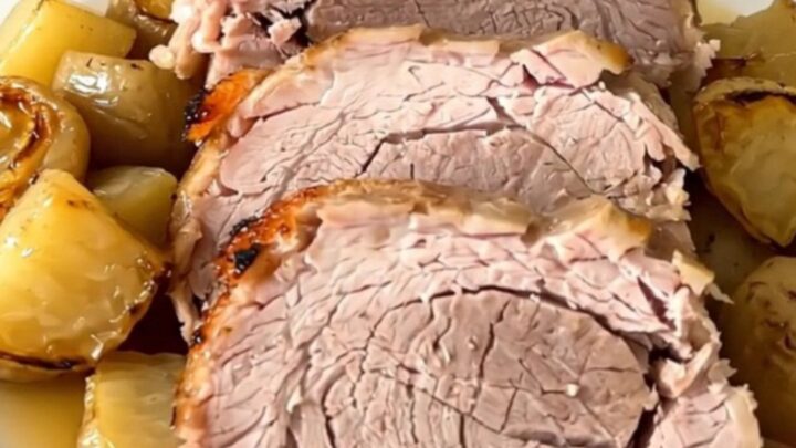 A tender, slow-cooked pork roast served on a white plate with glossy, cooked parsnips and carrots.