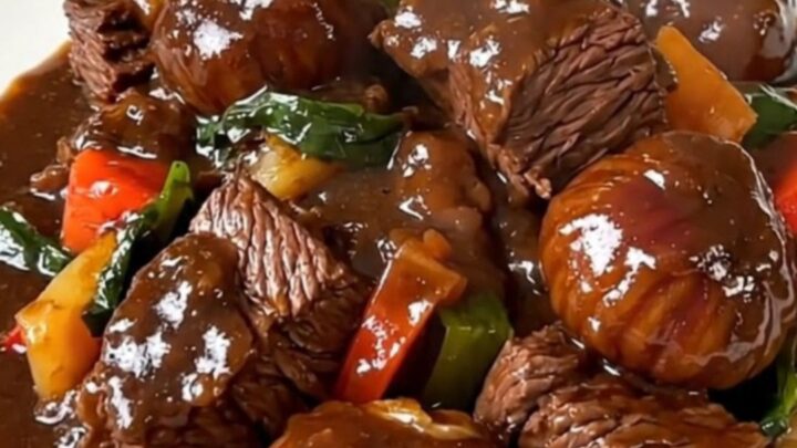 A steaming bowl of beef bourguignon with tender chunks of beef, bright carrots, and chestnuts in a rich red wine sauce.