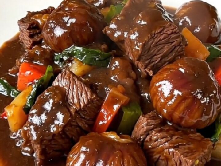 A steaming bowl of beef bourguignon with tender chunks of beef, bright carrots, and chestnuts in a rich red wine sauce.