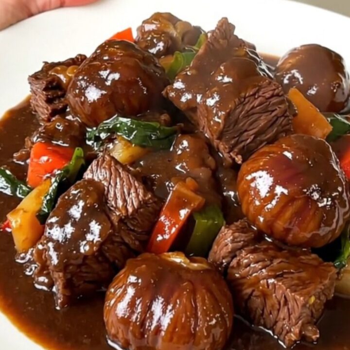 A steaming bowl of beef bourguignon with tender chunks of beef, bright carrots, and chestnuts in a rich red wine sauce.