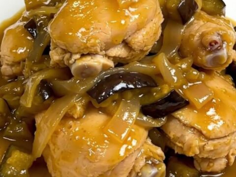 A steaming, glossy chicken and eggplant colombo served on a plain white round plate.