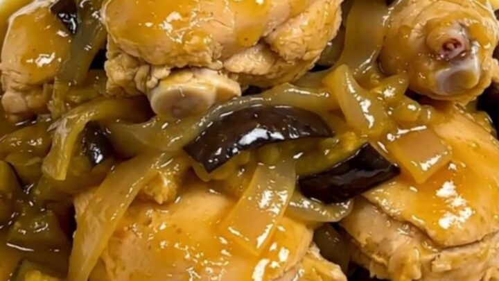 A steaming, glossy chicken and eggplant colombo served on a plain white round plate.