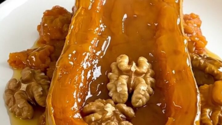A top-down view of raw butternut squash cubes and walnuts in a slow cooker, ready to be cooked with honey and cinnamon.