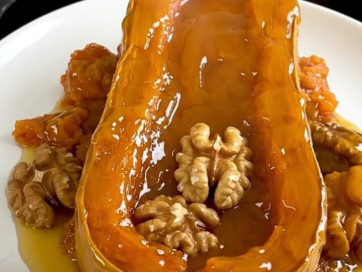 A top-down view of raw butternut squash cubes and walnuts in a slow cooker, ready to be cooked with honey and cinnamon.