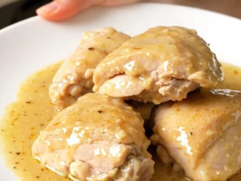 Finished Riesling chicken with tender onions in a white bowl, showing a glossy sauce.
