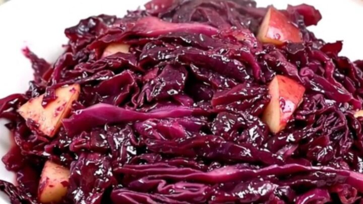 Vue de dessus d'un chou rouge braisé aux pommes et marrons dans une mijoteuse noire.