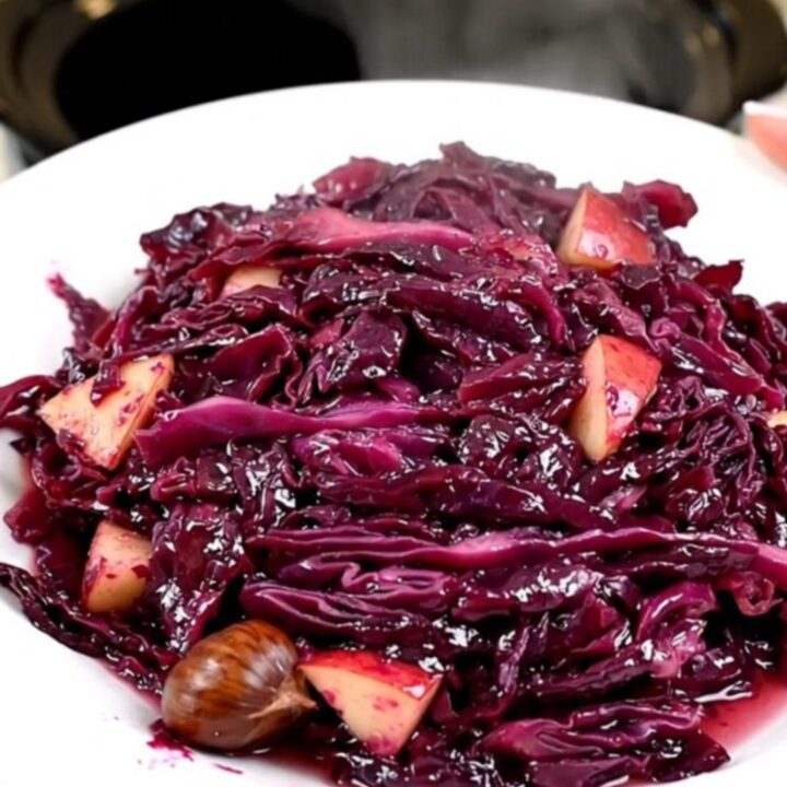 Vue de dessus d'un chou rouge braisé aux pommes et marrons dans une mijoteuse noire.