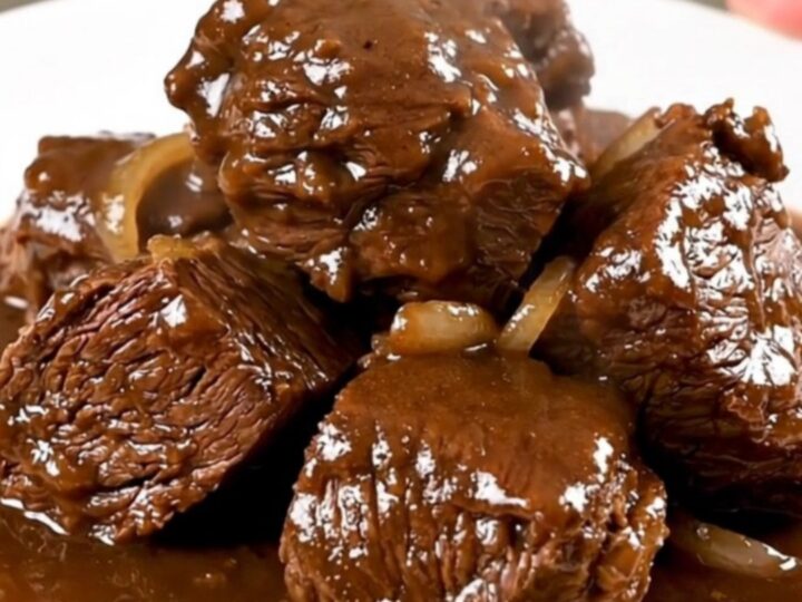 Bœuf braisé à la bière servi dans une assiette blanche avec une sauce brillante.