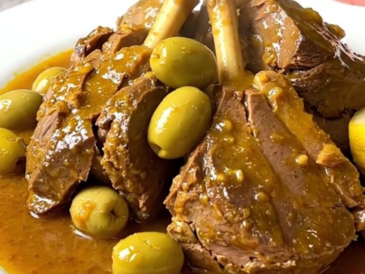 Slow cooker veal tagine served on a white plate with visible olives and preserved lemon wedges.