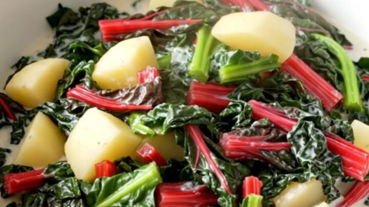 A rustic bowl filled with creamy diced potatoes and vibrant green Swiss chard in a rich, glossy cream sauce.