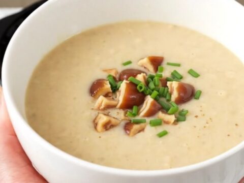 A white bowl filled with creamy, steaming parsnip and chestnut velouté topped with chopped chestnut pieces.