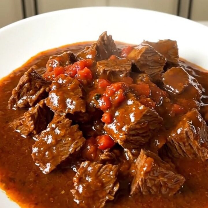 A close-up of a steaming, rich Sète-style beef stew served in a white bowl with a glossy tomato wine sauce.