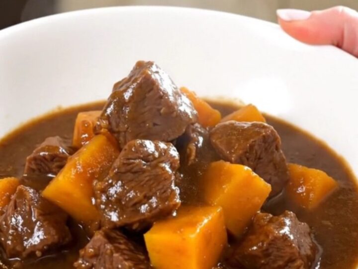 Ragoût de bœuf tendre servi dans une assiette blanche avec des morceaux de potimarron.