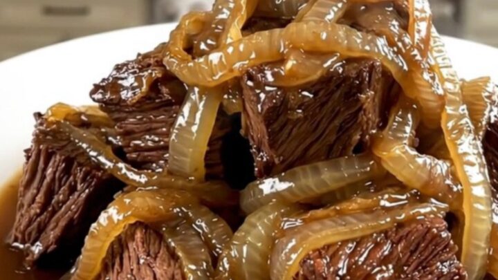 A close-up of glossy, tender braised beef neck with melting red onions served on a white plate.