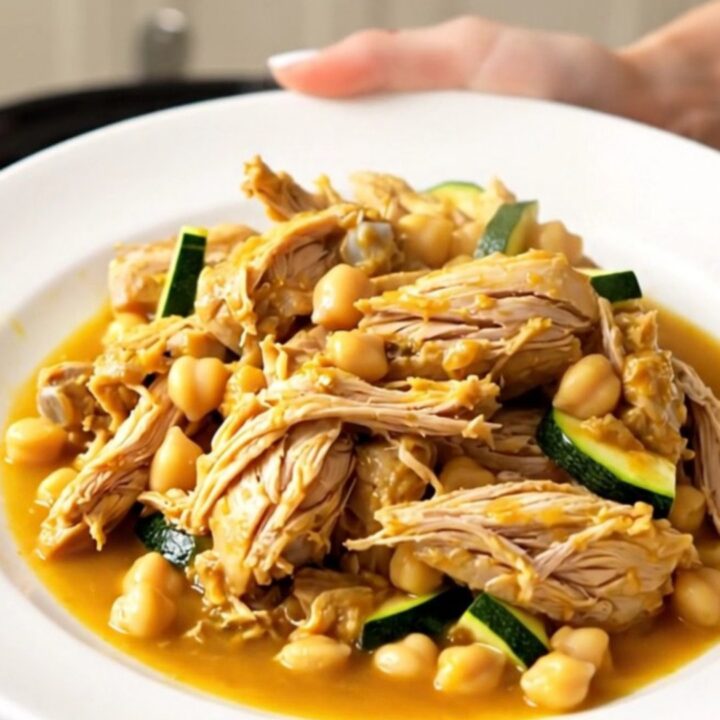 Tajine de poulet aux courgettes et pois chiches servi dans une assiette blanche, fumant et appétissant.